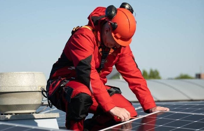 Werknemer op dak in bouw- en installatiekleding.