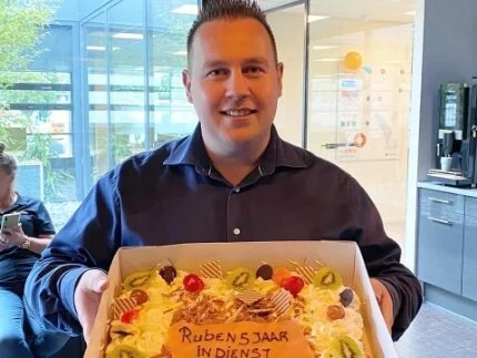 Ruben Borst met een taart in zijn hand vanwege 5 jarig jubileum.