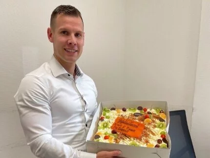 Nick Koppers met een taart in zijn hand vanwege 5 jarig jubileum.