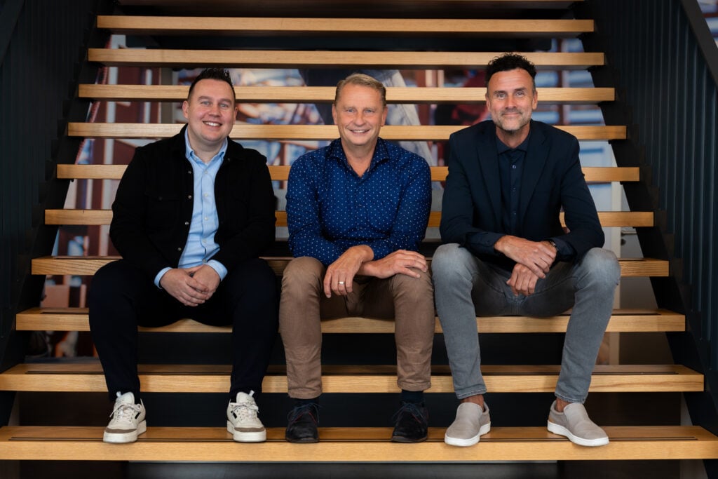 Ruben, Berry en Jeroen zitten naast elkaar op de trap in de showroom bij Van den IJssel.
