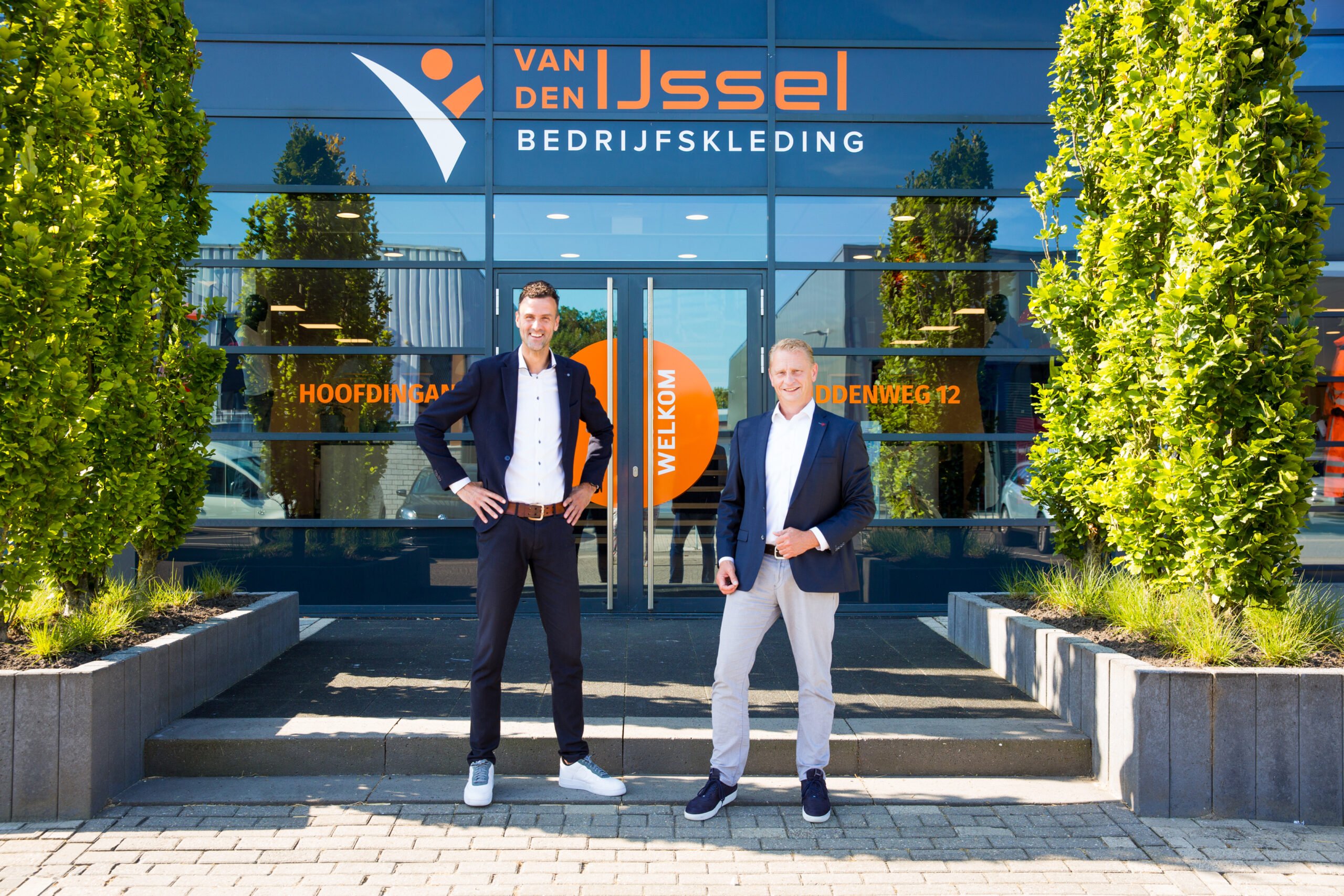 Berry en jeroen voor de entree buiten het pand, lachend.