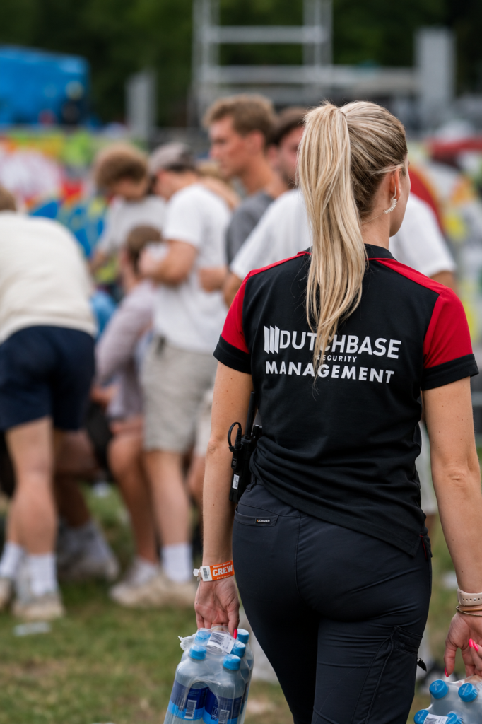 beveiliger loopt met water over het festivalterrein met werkkleding aan.