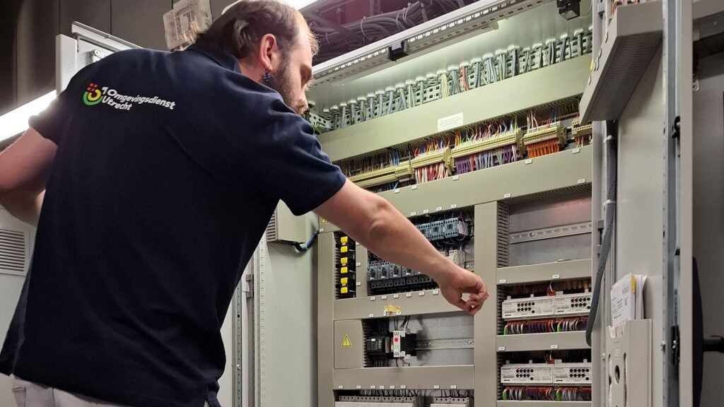ODU medewerker aan het werk in een installatiekast met bedrijfskleding aan
