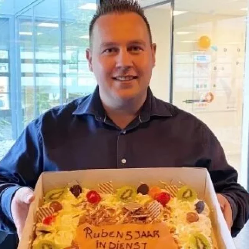 Ruben Borst met een taart in zijn hand vanwege 5 jarig jubileum.