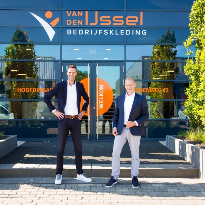 Berry en jeroen voor de entree buiten het pand, lachend.